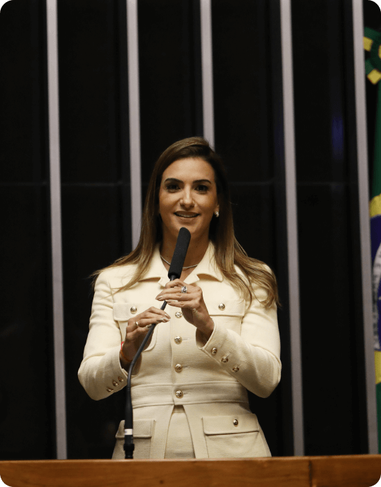 Deputada Roberta Roma discursando no plenário, destacando-se por seu engajamento político e compromisso com a responsabilidade cívica. A imagem reflete uma postura confiante e dedicada em prol de suas pautas.