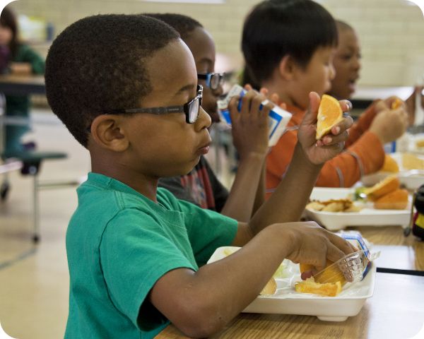 Criança comendo fruta na escola, representando os benefícios da alimentação saudável nas escolas públicas